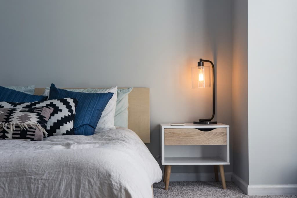 Modern bedroom with layered pillows and a glowing bedside lamp
